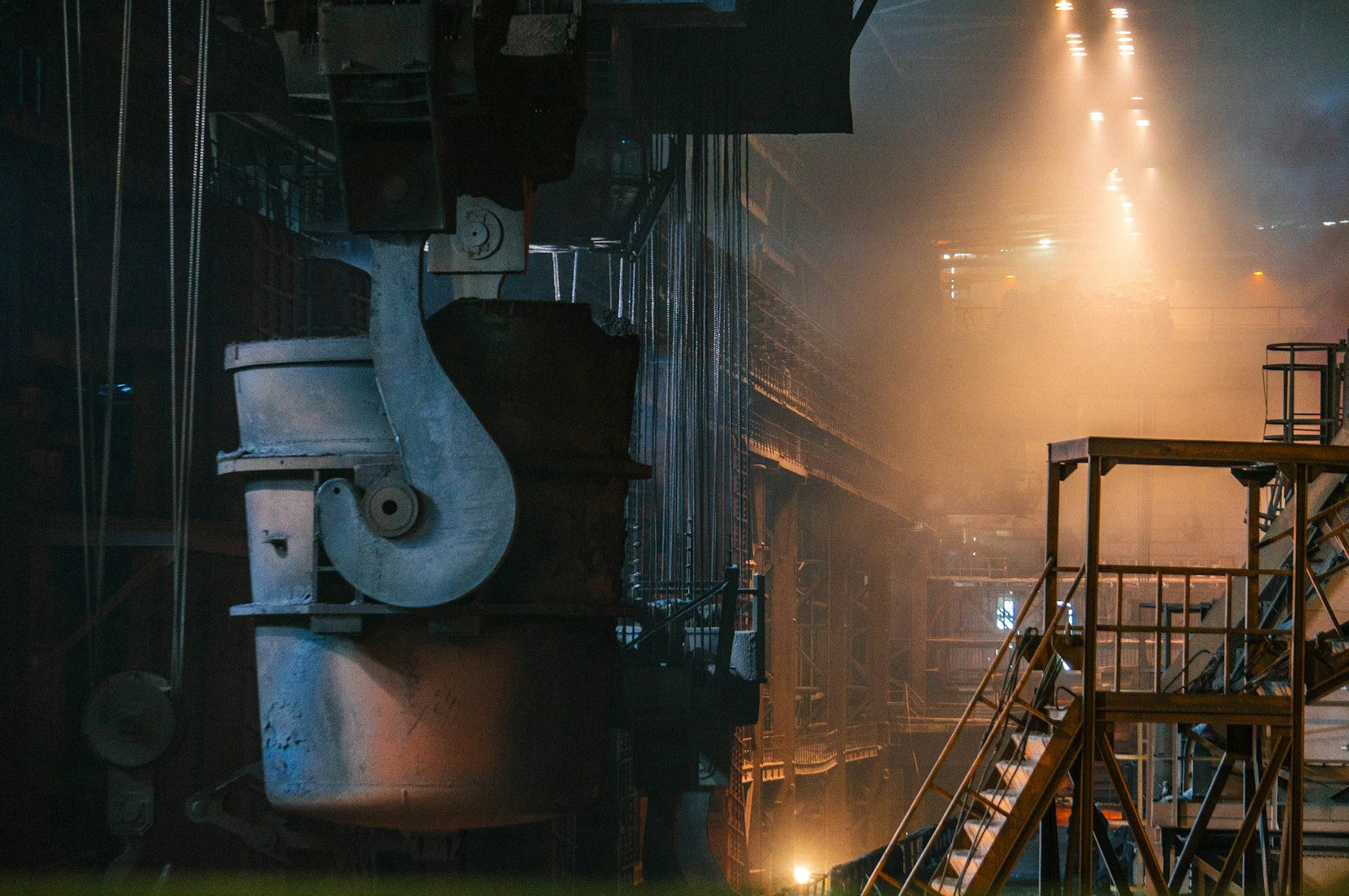 Interior of a steel plant with an overhead ladle and gantry.